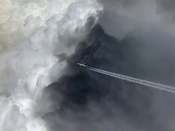 Airplane flying above dark dramatic clouds
