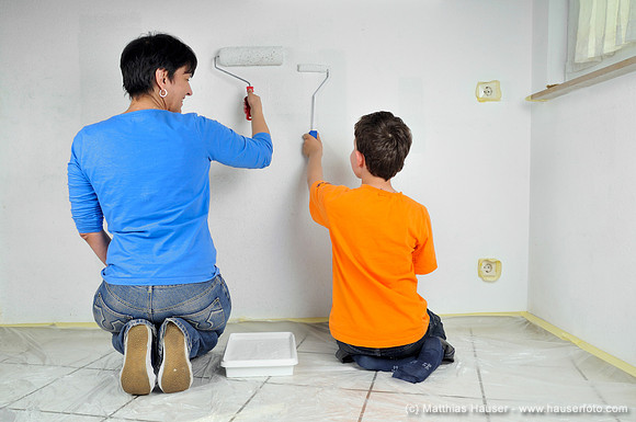 Malerarbeiten, Mutter und Sohn streichen Wand mit Farbrolle - Paintwork, mother and son painting wall with paint rollers