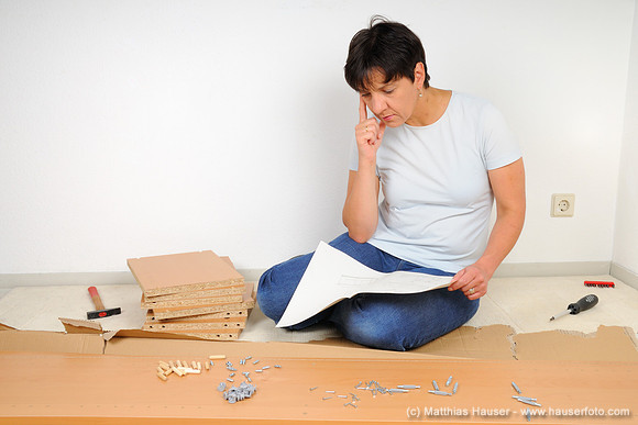 Frau beim Möbel zusammenbauen, Lesen der Anleitung - Woman assembling furniture, reading the instructions