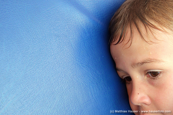 Exhausted and wet boy is lying on a blue mat (after swimming)