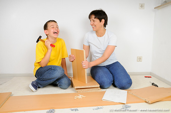 Mutter und Sohn beim Möbel zusammenbauen, Montage Regal-Brett - Mother and son assembling furniture, assembling the shelves