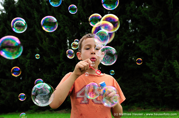 Junge pustet viele bunte Seifenblasen - Boy blowing many colourful bubbles